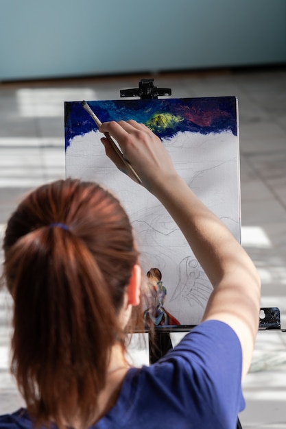 若い10代の女性アーティストは大理石のタイルの床に座っています。油絵の具で描く過程の女性。