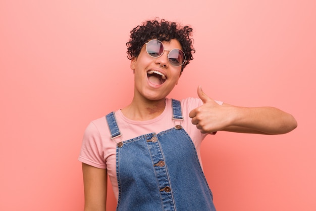 Young teenager woman smiling and raising thumb up