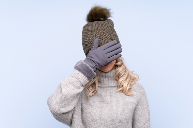 La giovane donna dell'adolescente con la copertura del cappello dell'inverno osserva a mano