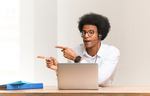 Young telemarketer black man pointing to the side with finger