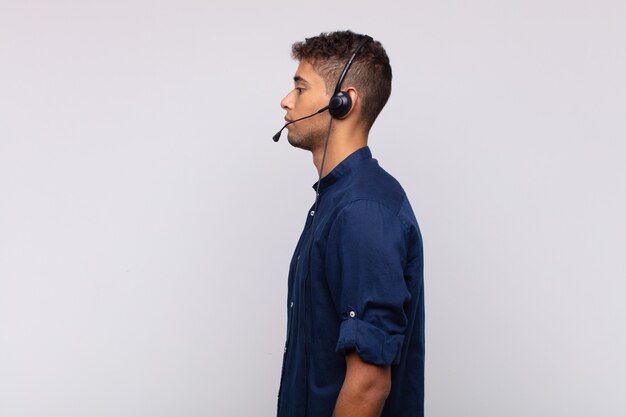 Photo young telemarketer man on profile view looking to copy space ahead, thinking, imagining or daydreaming