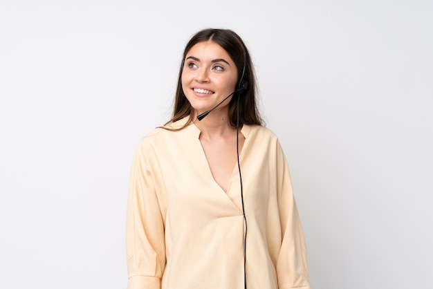 Young telemarketer woman over isolated white wall laughing and looking up