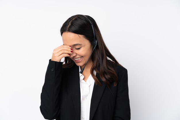 Young telemarketer woman isolated on white wall laughing