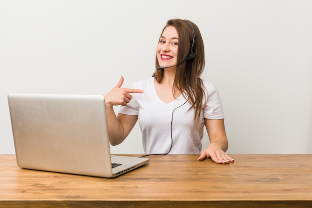 Young telemarketer woman person pointing by hand to a shirt copy space, proud and confident