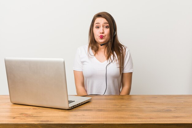 Young telemarketer woman shrugs shoulders and open eyes confused.