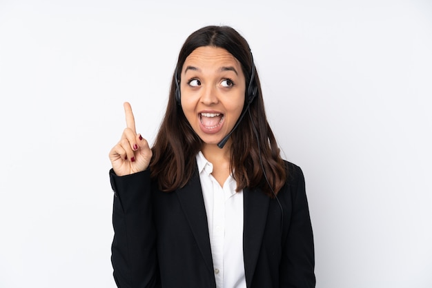 Young telemarketer woman on white wall intending to realizes the solution while lifting a finger up