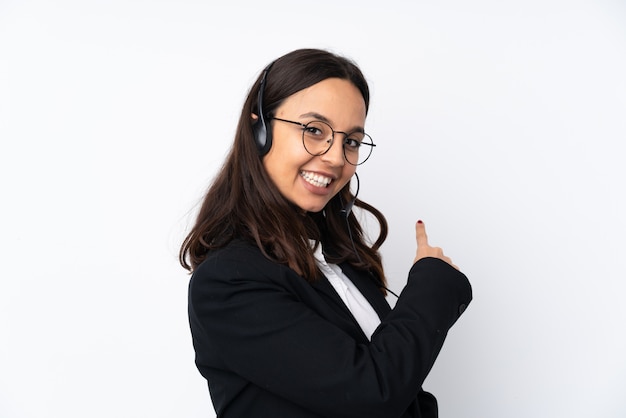 Photo young telemarketer woman on white wall pointing back