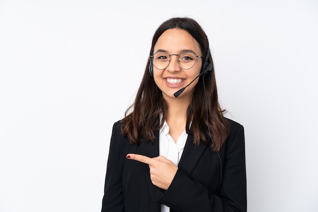 Young telemarketer woman on white wall surprised and pointing side