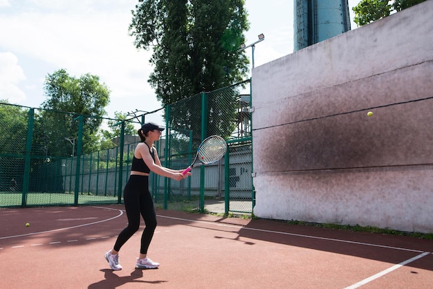 若いテニス女の子が壁でプロのスポーツをしている