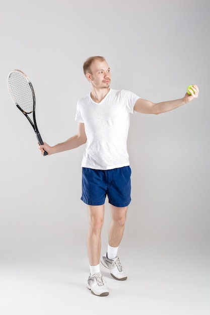 Young tennis player plays tennis on a grey