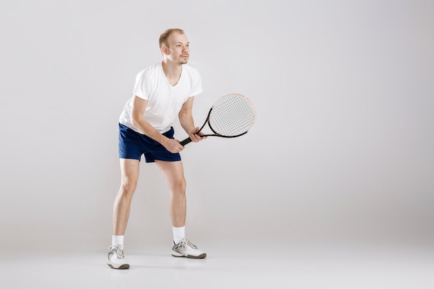 Young tennis player plays tennis on a grey