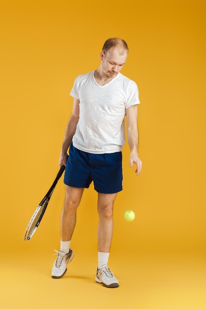 Young tennis player plays tennis on a yellow