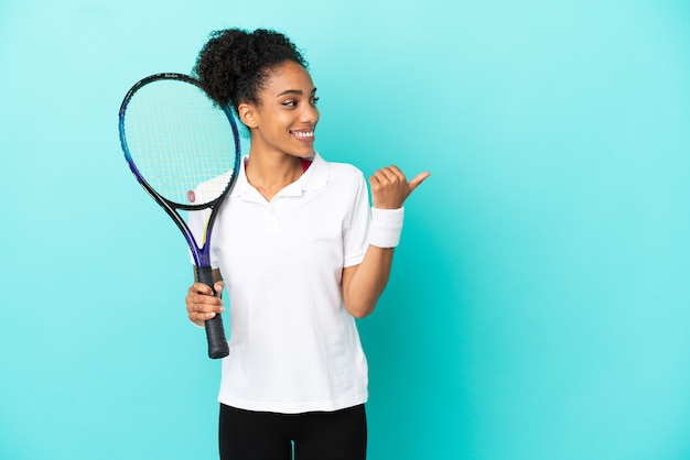 Photo young tennis player woman isolated on blue background pointing to the side to present a product