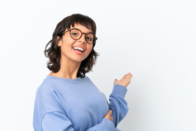 Young tennis player woman over isolated pink wall pointing to the side to present a product