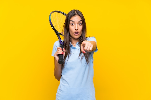 Foto giovane donna del tennis sopra la parete gialla isolata sorpresa e indicando parte anteriore