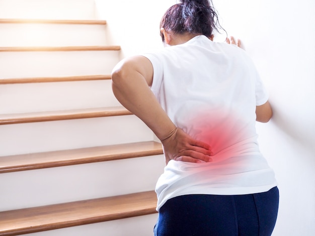 Photo young thai asian woman suffering low back pain and waist lumbar pain when walking up the stairs.