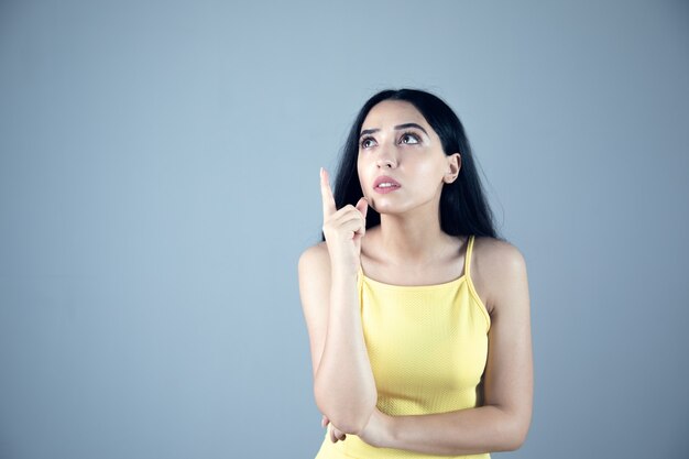 The young thinking woman on grey