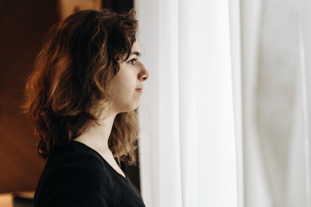 Photo young thoughtful girl with curly hair looking to window