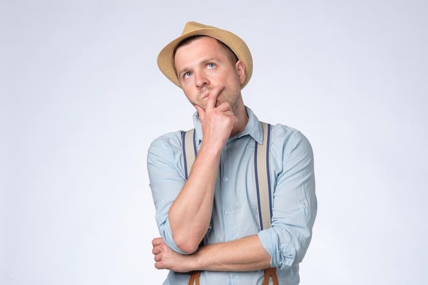 Young thoughtful man looking up generating idea, making plans for future. Studio shot