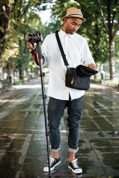 Young thoughtful man in park with camera