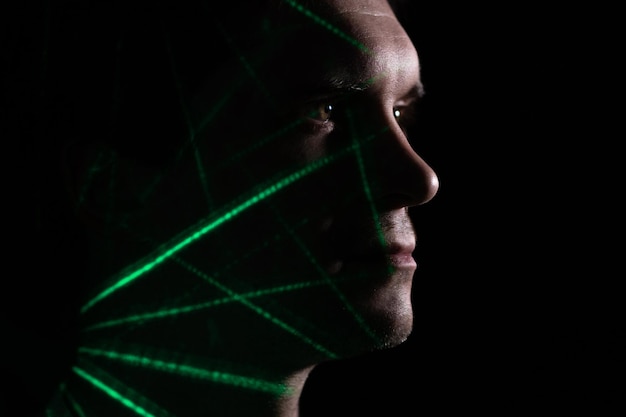 A young thoughtful man in profile, silhouette on a black
background, projections of colored patterns on his face, man and
technology, concept