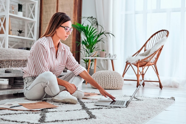 Photo young thoughtful woman working on laptop sitting on floor surfing net copy space