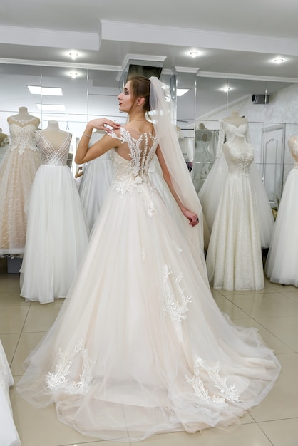 Young and tiny bride in wedding dress in salon