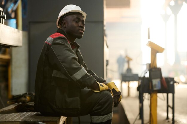 Young tired African American workman resting at break after work