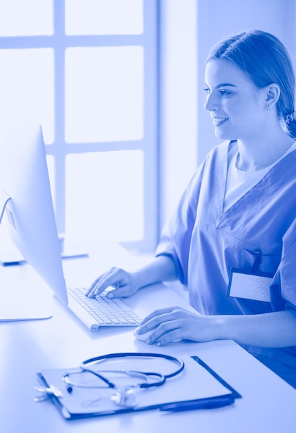 Young tired exhausted woman sitting at desk working on computer with medical documents