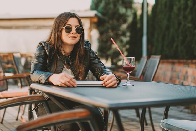 コーヒー ショップに座っているラップトップで若い疲れて働く女性