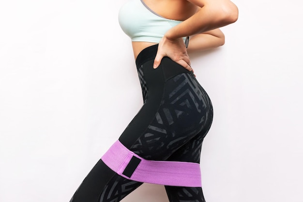 A young toned woman with a fitness band on her thighs for the lower body legs and buttocks workout