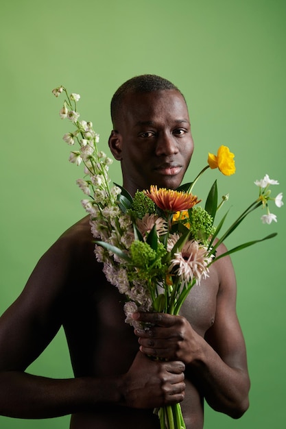 Young topless man of african ethnicity holding flower bouquet