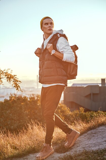 Young tourist blogger in orange hat walks at backgroung is sunrise