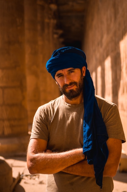 A young tourist in a blue turban visiting the Edfu Temple in the morning near Aswan city. Egypt