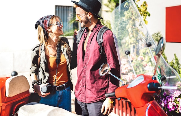 Young tourist couple having fun together at scooter moped ride - Hipster guy having fun outdoors with beautiful girlfriend - Happy travel mood and life style concept on spring day