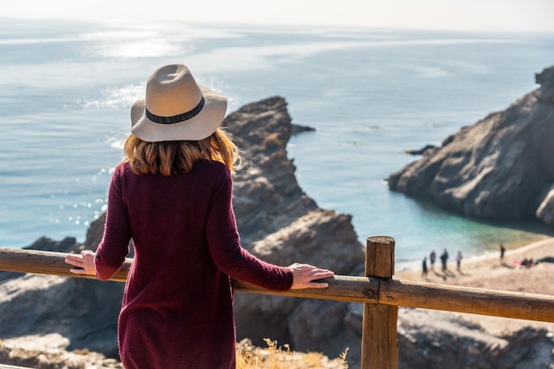 A young tourist girl with a hat looking at the beautiful Cala Penon cut off a virgin and hidden beach in Almeria Mediterranean sea on the coast Almanzora Caves Almeria