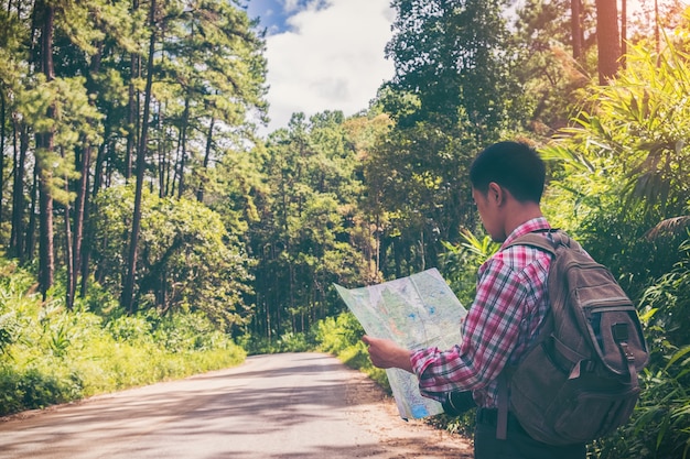 A young tourist looking to the map on road in the park