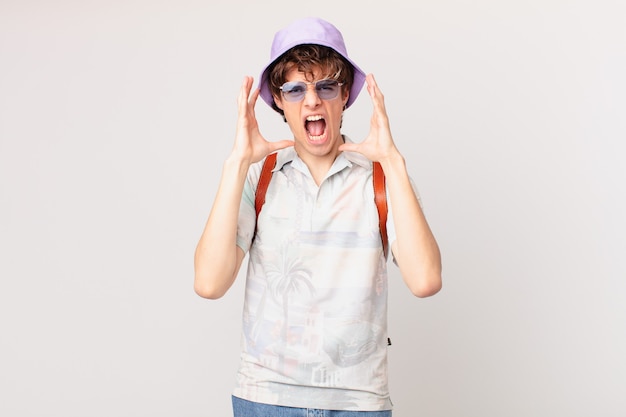 Young tourist man screaming with hands up in the air