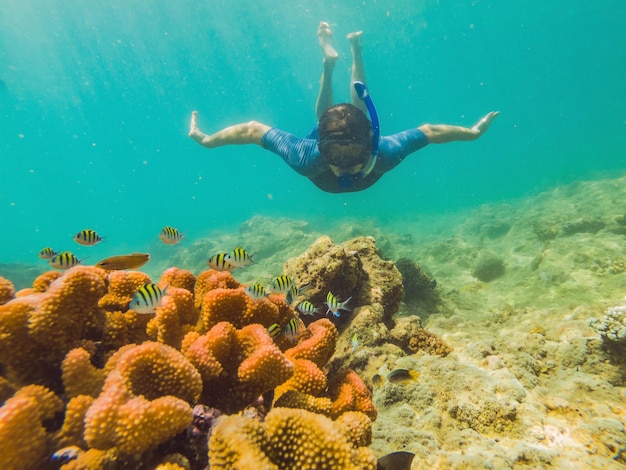 Giovane turista che nuota nel mare turchese sotto la superficie vicino alla barriera corallina con maschera da snorkeling per le vacanze estive