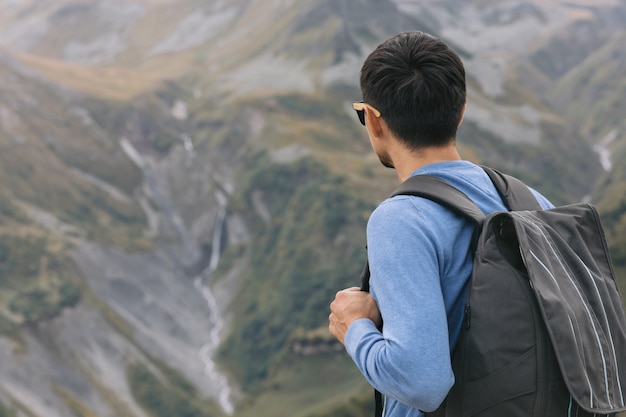 霧の日にジョージア州コーカサス山脈を背景にバックパックを持った若い観光客の男。コピースペース