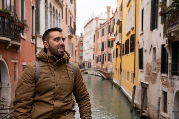 Photo young tourist man with beard on the canals of venice among colorful facades