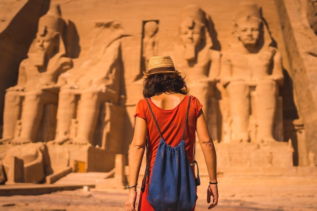 A young tourist in a red dress entering the Abu Simbel Temple in southern Egypt