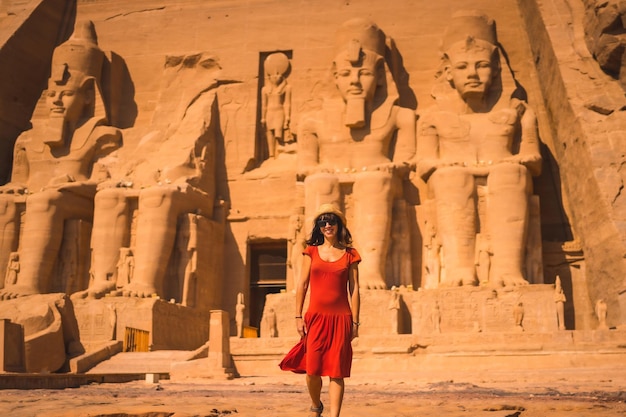 A young tourist in a red dress entering the Abu Simbel Temple in southern Egypt