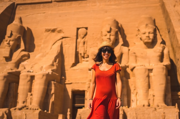 Photo a young tourist in a red dress smiling at the abu simbel temple