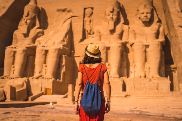 A young tourist in red dress walking towards the Abu Simbel