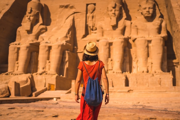 A young tourist in red dress walking towards the Abu Simbel