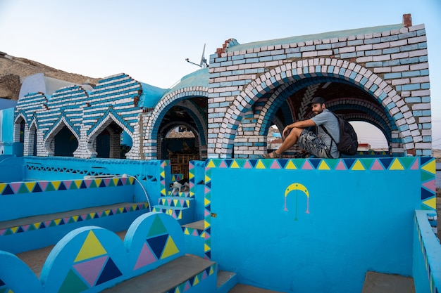 A young tourist sitting on a beautiful terrace of a traditional blue house in a Nubian village near the city of Aswan. Egypt