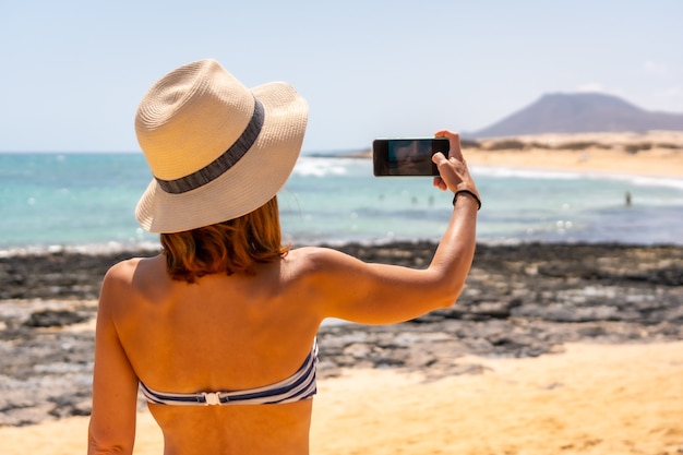 A young tourist taking a photo on the beaches of the dunes of the Corralejo Natural Park, Fuerteventura, Canary Islands. Spain