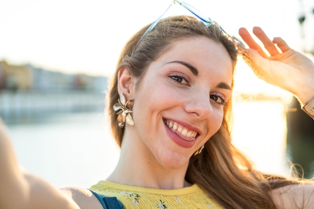 Young tourist taking a selfie photo at a sunset Woman on summer vacation with a smile