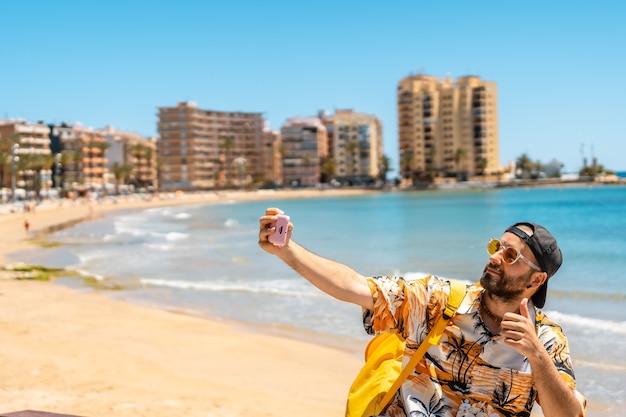 A young tourist taking a selfie at Playa del Cura in the coastal city of Torrevieja, Alicante, Valencian Community